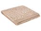 Serviette de bain beige pliée avec un motif géométrique et un logo brodé.