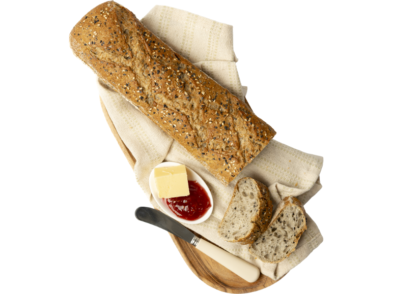 Pain multicéréales avec beurre et confiture sur un plateau en bois.