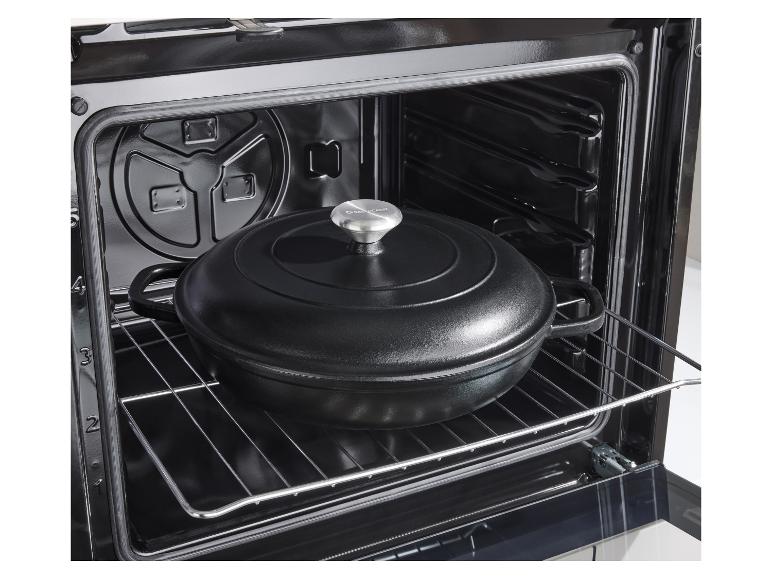 Marmite en fonte noire avec couvercle à l'intérieur d'un four sur une grille.