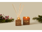 Diffuseur à bâtonnets et bougie parfumée Marshmallow Fireside, entourés de pin et de baies.
