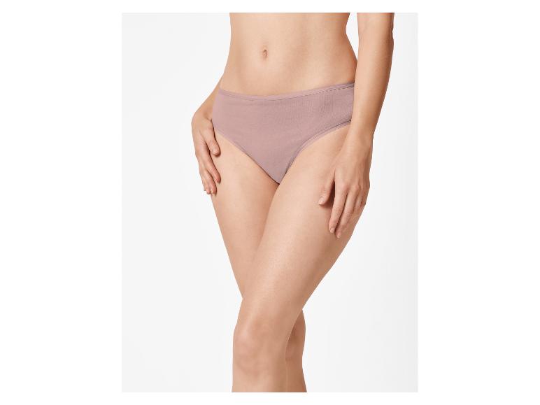 Femme en culotte beige, les mains sur les hanches.