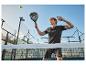Homme en tenue de sport noire jouant au padel avec une raquette et une balle.