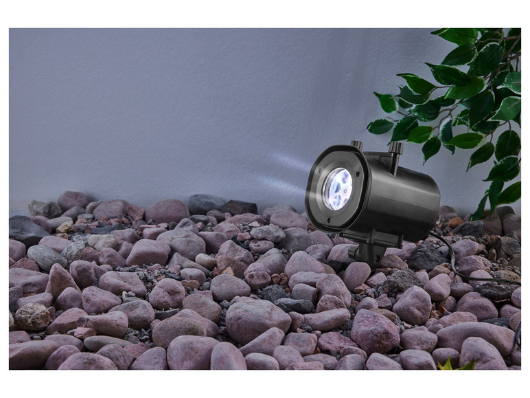 Un projecteur noir avec des rayons lumineux sur des pierres.