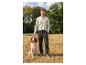 Homme en chemise à manches longues et pantalon caressant un chien à l'extérieur.