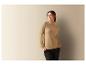 Une femme portant un pull beige à col roulé et un pantalon noir.