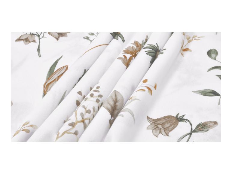 Tissu blanc avec un délicat motif floral dans des tons bruns et verts, plié.