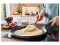 Une crêpe est cuite dans une poêle sur une plaque à induction.