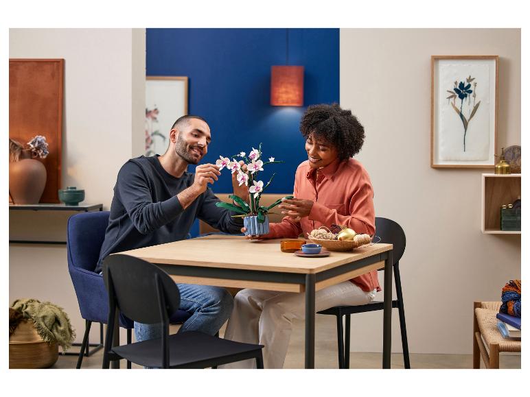 Un homme et une femme assemblent un set LEGO Orchidée sur une table en bois.