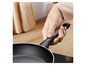 Une poêle noire avec une poignée Tefal.