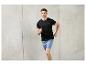Un homme en t-shirt noir et short bleu en train de courir.