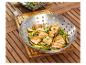 Saumon et edamames grillés dans un wok en acier inoxydable.