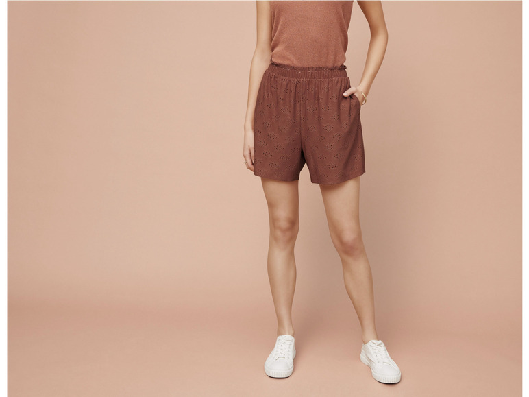 Une femme portant un short marron et des baskets blanches.