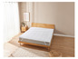 Un protège-matelas blanc sur un cadre de lit en bois