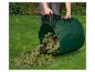 Un sac de jardin vert rempli de feuilles, sur l'herbe.