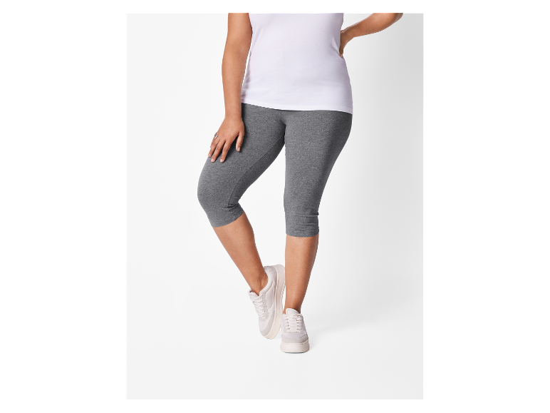 Femme portant un t-shirt blanc et des leggings gris.