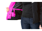 Femme en veste noire avec doublure rose et pantalon bleu foncé.