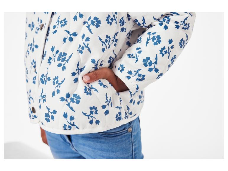 Blouson matelassé à fleurs bleu marine sur fond blanc et jeans.