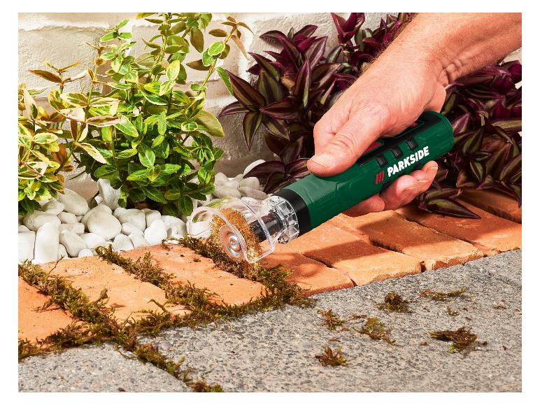 Homme retirant la mousse d'un pavé en briques avec une brosse à joints électrique.