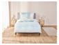 Une parure de lit bleu clair à motif blanc sur un lit avec deux tables de chevet.