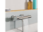 Un robinet de baignoire chromé avec un bec en cascade sur un mur de carreaux gris.