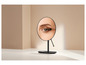 Un miroir de maquillage noir avec un gros plan d'un œil et un pinceau.