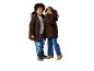 Deux enfants en vestes polaires marron et jeans, l'un chuchotant à l'autre.