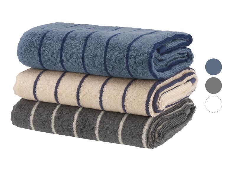 Pile de trois serviettes rayées bleu, beige et gris.
