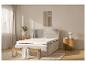 Un lit gris avec un matelas blanc, un banc en bois et des tables de chevet.
