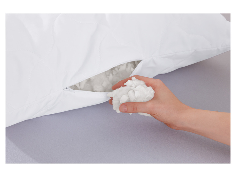 Une taie d'oreiller blanche avec un rembourrage visible en fibres blanches et douces.