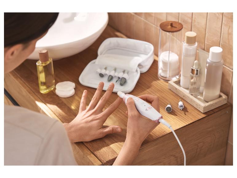 Femme utilisant un set électrique de manucure et pédicure, avec des produits de beauté à proximité.
