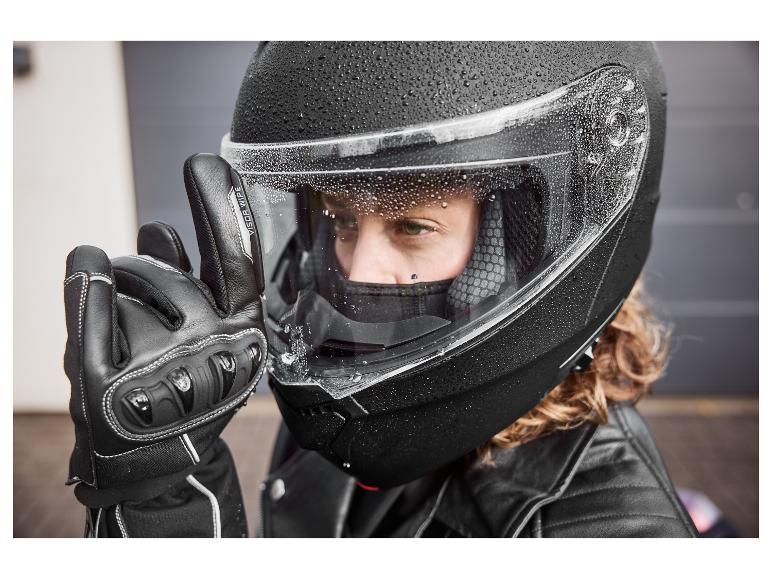 Personne avec un casque de moto noir avec des gouttes d'eau et un gant noir avec le texte 'VISOR WIPE'.
