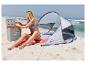 Femme sur la plage assise près d'une tente et d'une glacière, ouvrant une bouteille.
