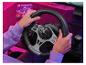 Mains tenant un volant de jeu avec levier de vitesse, sur un bureau éclairé en rose.