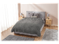 Une couverture grise matelassée sur un lit gris dans une chambre à coucher.