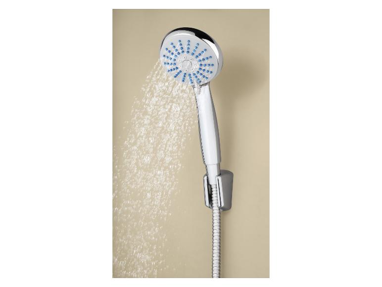 Pommeau de douche chromé avec jet d'eau sur un mur beige.