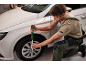 Un homme utilise une clé dynamométrique pour serrer la roue d'une voiture blanche.
