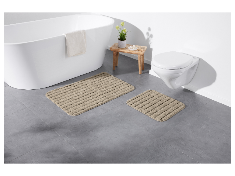Tapis de bain beiges sur un sol en carrelage gris.