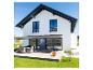 Maison moderne avec store gris au-dessus d'une terrasse en bois et mobilier de jardin.