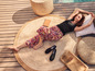 Une femme est allongée sur un tapis en jute avec des espadrilles, un top noir et un pantalon rayé.