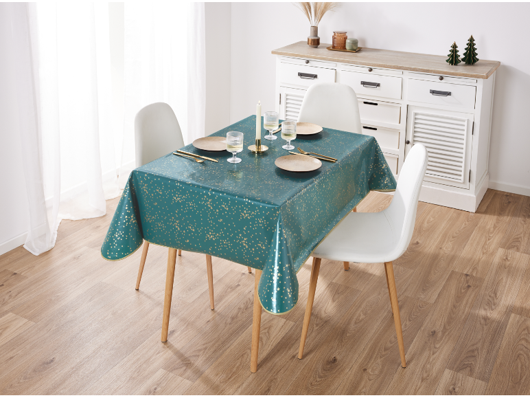 Table à manger avec une nappe sarcelle à étoiles dorées, dressée avec assiettes, verres et couverts.