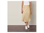 Une femme porte une jupe en satin beige et des baskets blanches.