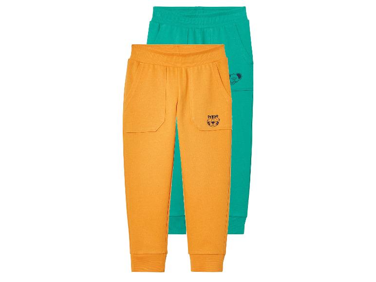 Deux pantalons de jogging pour enfants, un orange et un vert.
