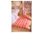 Chambre avec literie à motif de citrons, oreillers roses et tapis rayé orange et rose.