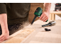 Homme utilisant un aspirateur à main pour nettoyer la sciure d'une surface en bois.