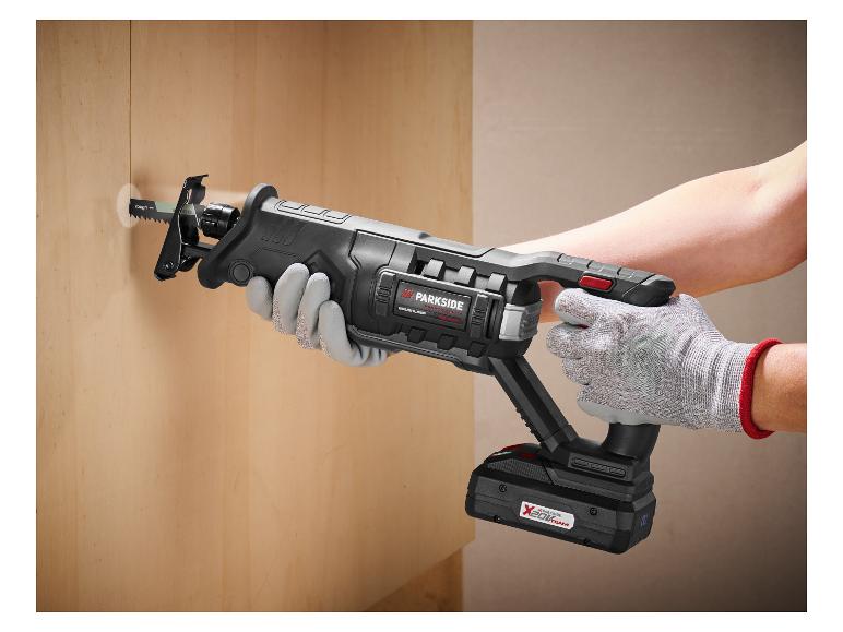 Une personne utilise une scie sabre sans fil pour découper un trou dans un mur en bois.