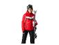 Femme en veste de ski rouge et pantalon de ski noir tenant des skis.