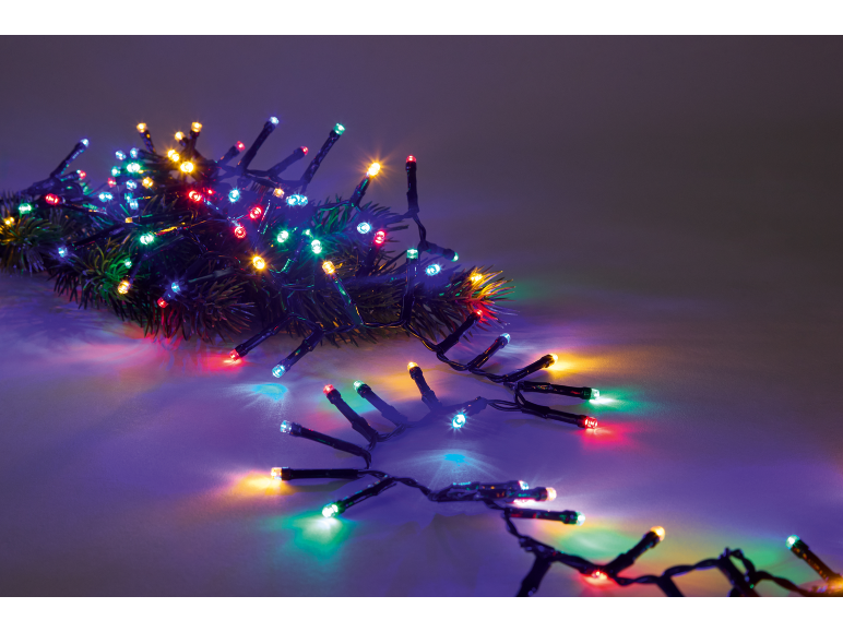 Guirlande lumineuse de Noël colorée sur une branche de sapin, ambiance festive.