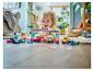 Un enfant joue avec des voitures de course LEGO Duplo et un portique de départ sur un parquet.