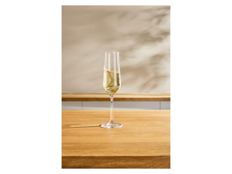 Une flûte remplie de vin pétillant sur un comptoir en bois.