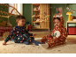 Deux enfants en pyjama de Noël jouent sur le tapis.